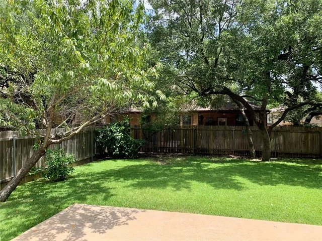 a backyard of a house with lots of plants and large tree