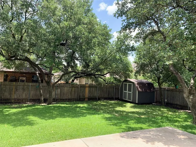 a view of a backyard with large trees and wooden fence