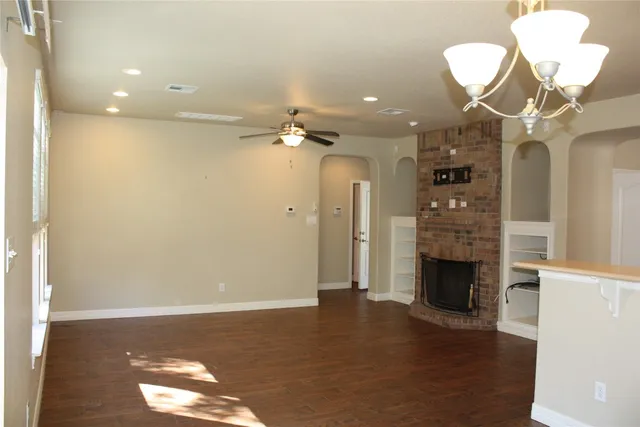 an empty room with wooden floor fan and windows