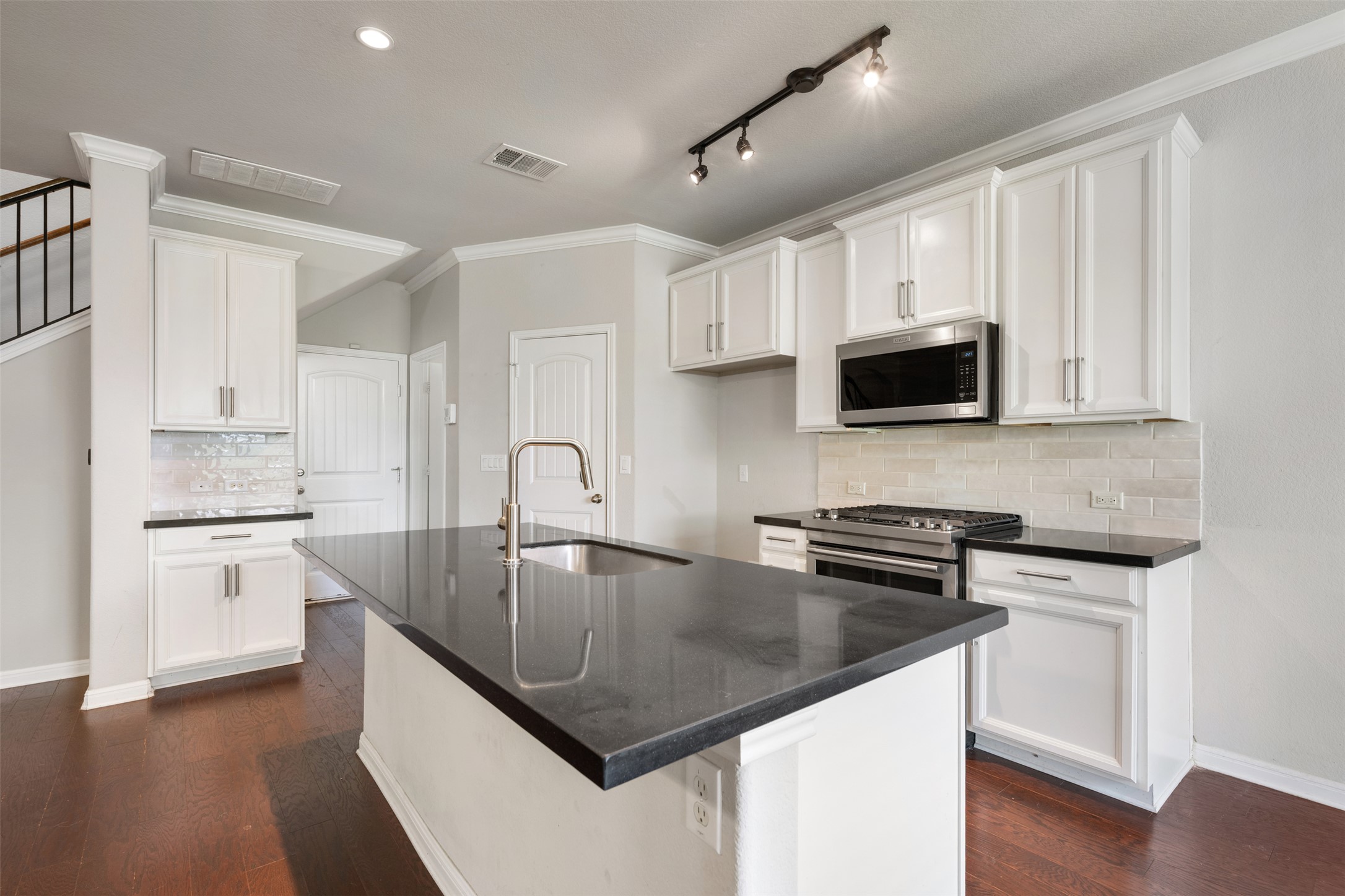 211 Parable Cove Pflugerville, TX 78660 - Photo 11 of 40 Kitchen featuring a center island with a stainless steel sink, dark countertops, white cabinetry, and stainless steel appliances