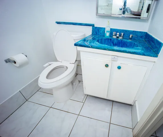 a bathroom with a granite countertop sink a toilet and mirror