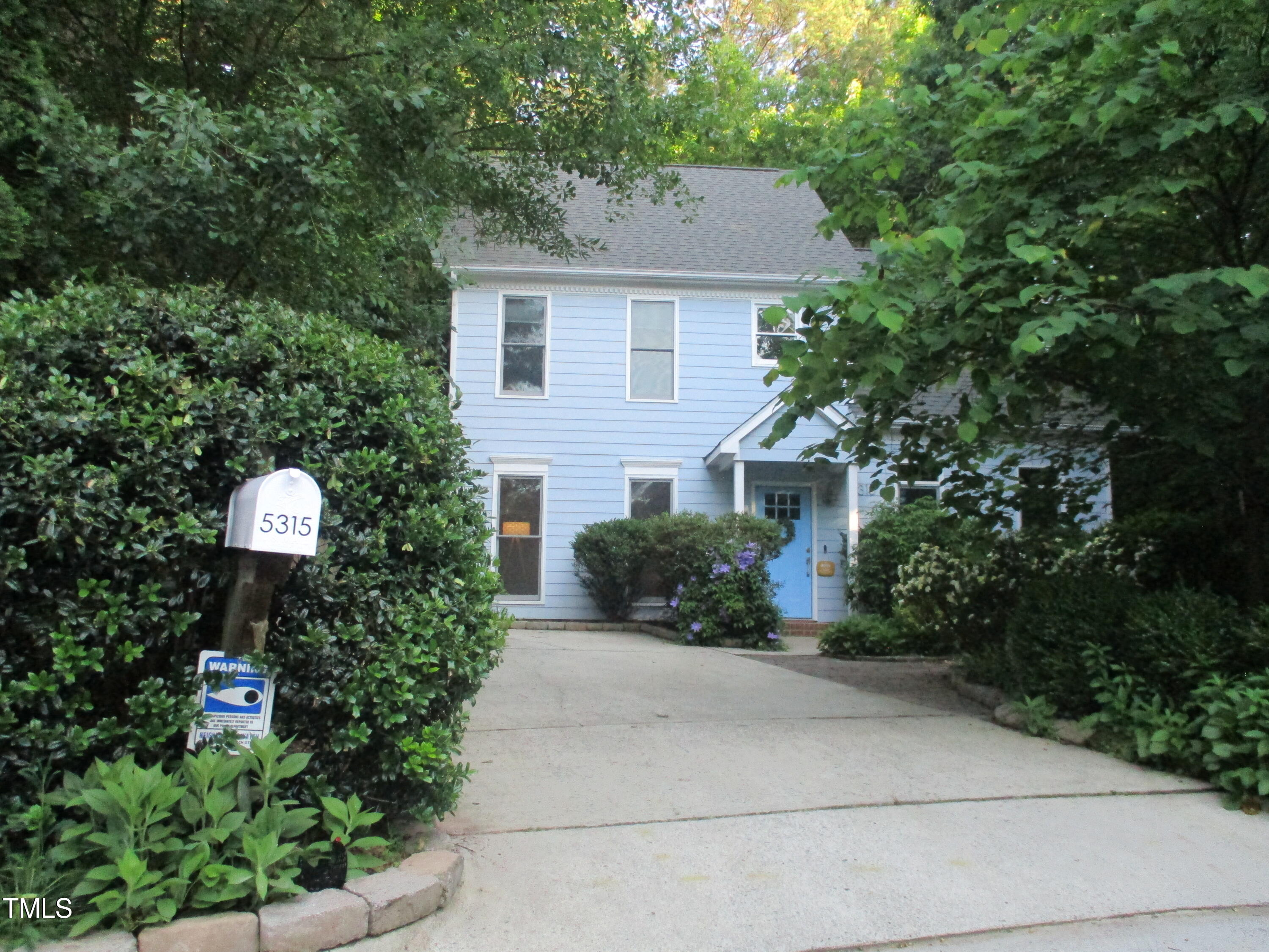 a front view of a house with plants and trees