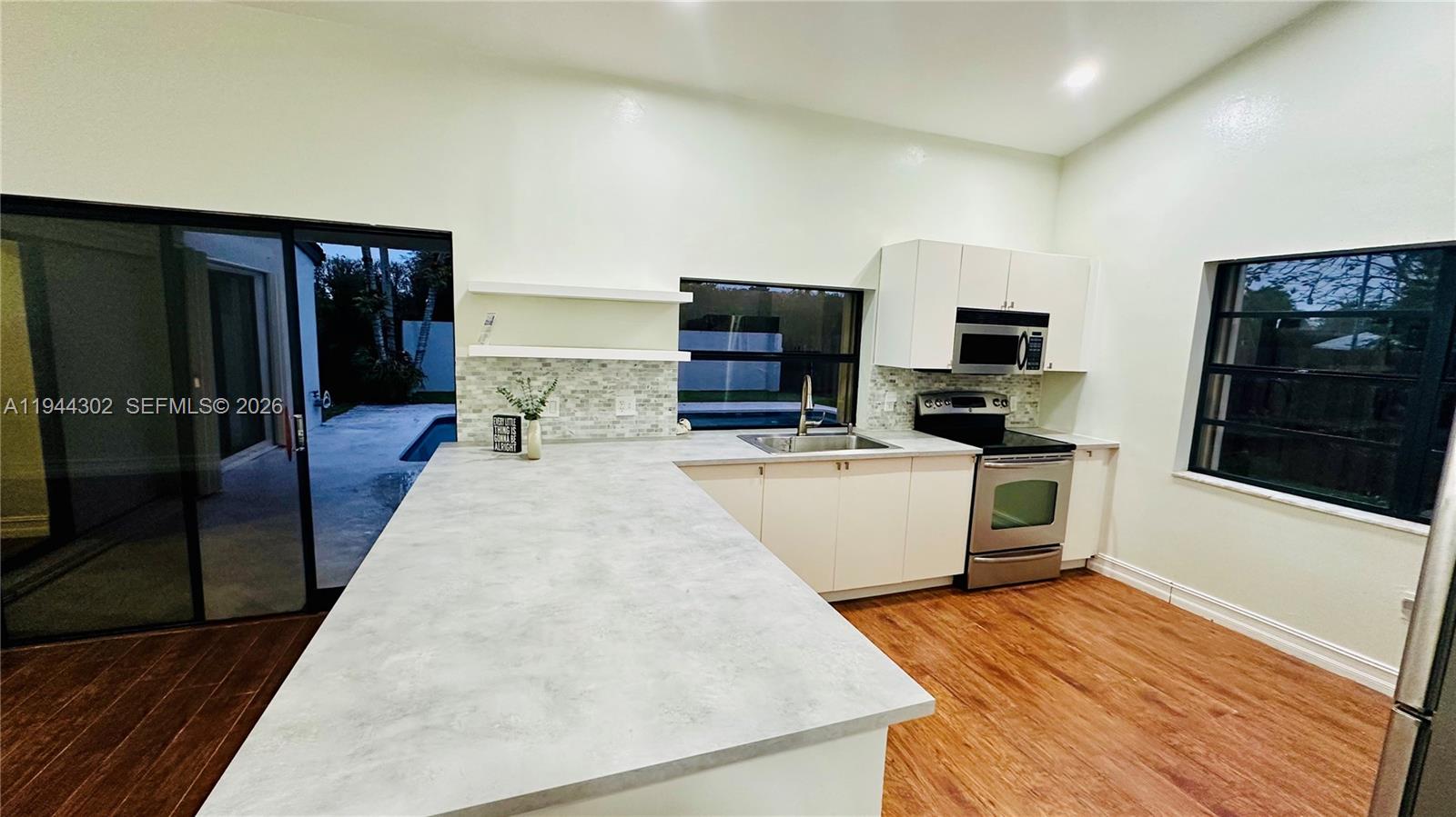 528 Southwest 166th Terrace Weston, FL 33326 - Photo 4 of 14 a large white kitchen with wooden floor and a sink