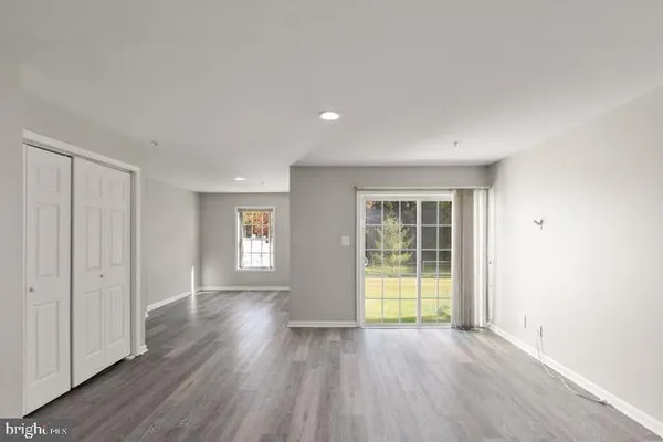 a view of an empty room with wooden floor and window