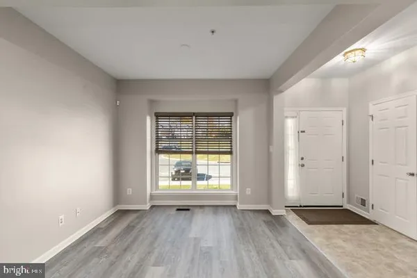 a view of an empty room with wooden floor and window