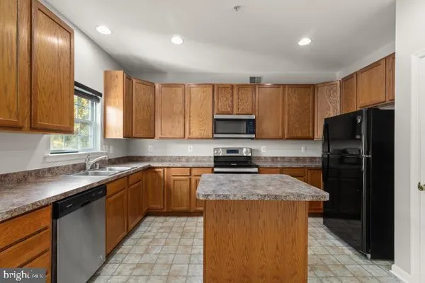 a kitchen with stainless steel appliances granite countertop a refrigerator a sink a stove a microwave and wooden cabinets