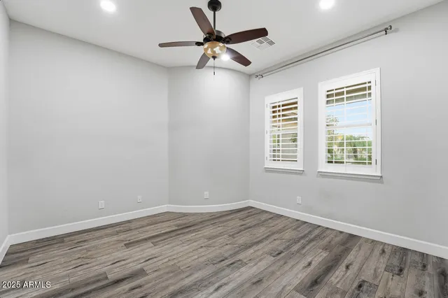 a view of a livingroom with an empty space a ceiling fan and wooden floor
