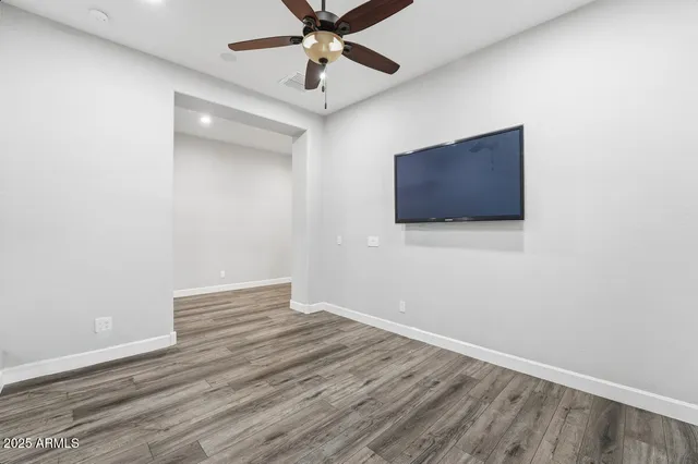 a view of a room with wooden floor and a ceiling fan