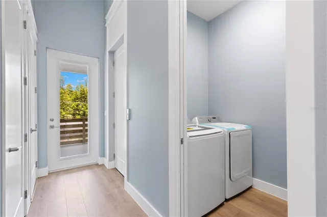 a view of an empty room with wooden floor and a kitchen