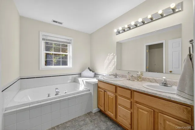 a bathroom with a tub a double vanity sink and a mirror