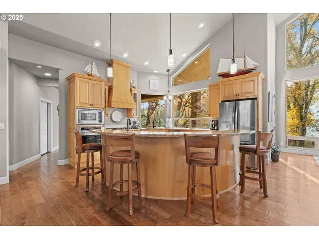 a dining room with stainless steel appliances kitchen island granite countertop a table chairs and a living room view