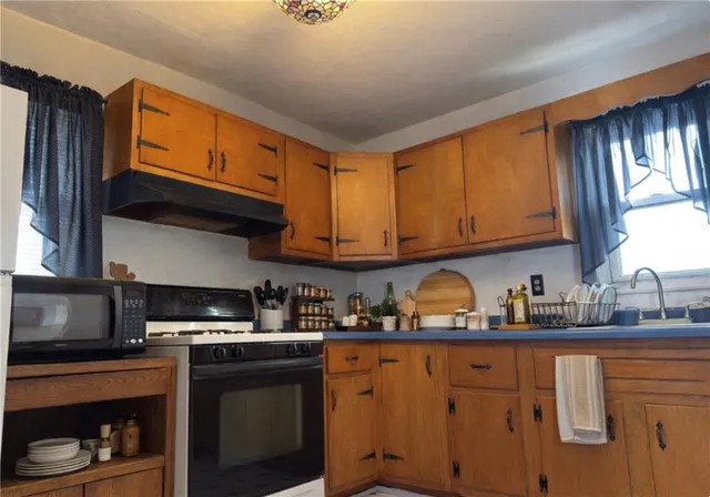 a kitchen with stainless steel appliances granite countertop a sink a stove a refrigerator cabinets and a window