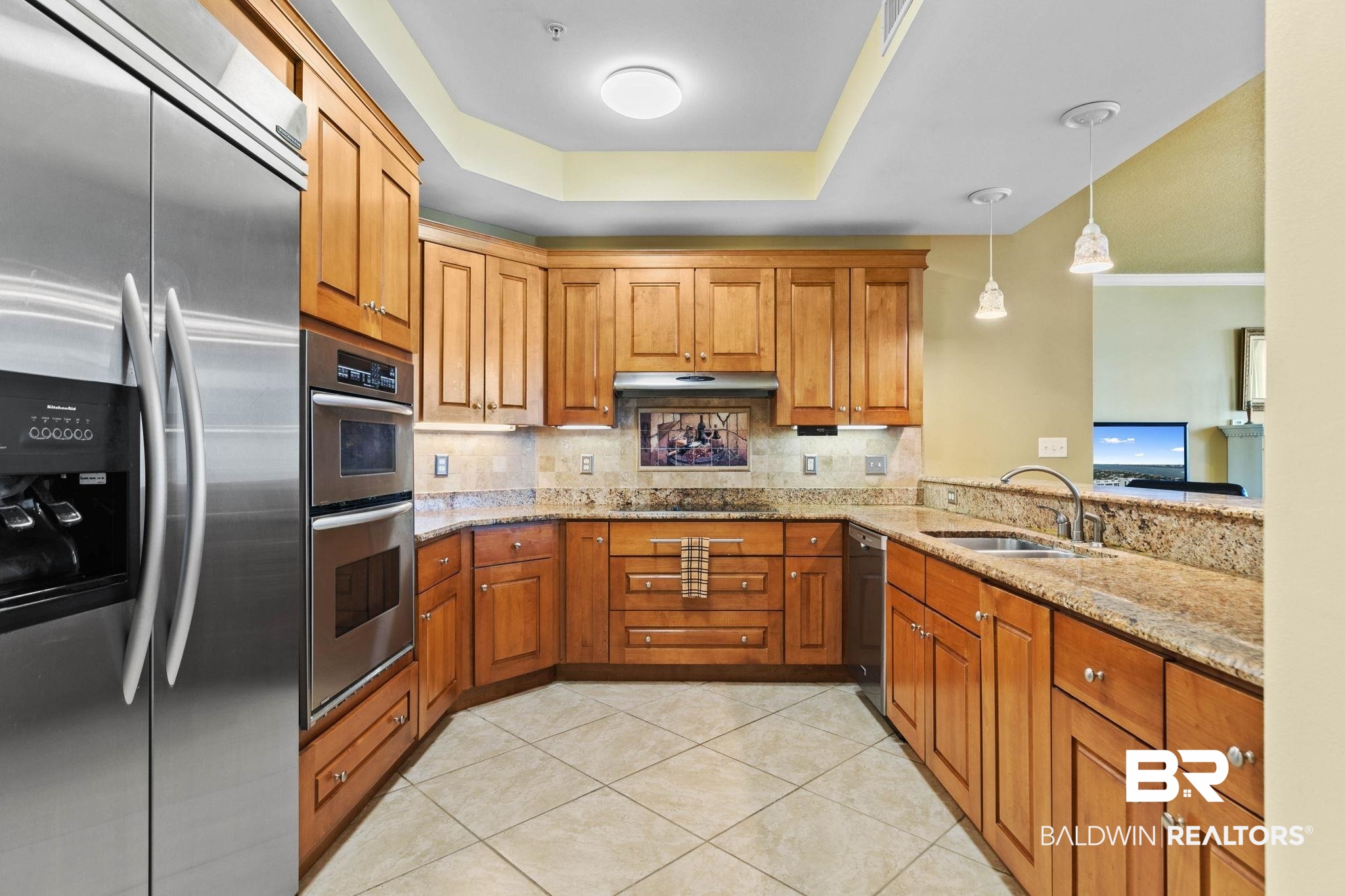 28250 Canal Road, Unit 208 Orange Beach, AL 36561 - Photo 16 of 53 Kitchen featuring stainless steel appliances, light stone counters, backsplash, decorative light fixtures, and a raised ceiling