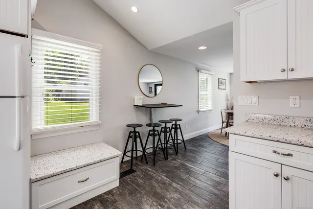 a kitchen with granite countertop a table chairs a sink dishwasher and cabinets with wooden floor