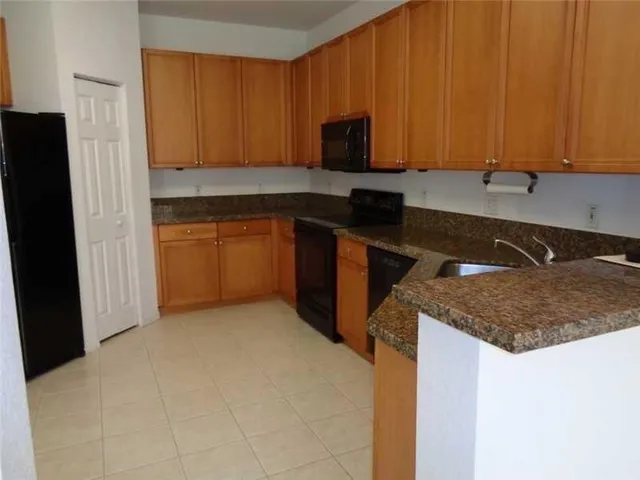 a kitchen with granite countertop a sink stove and microwave