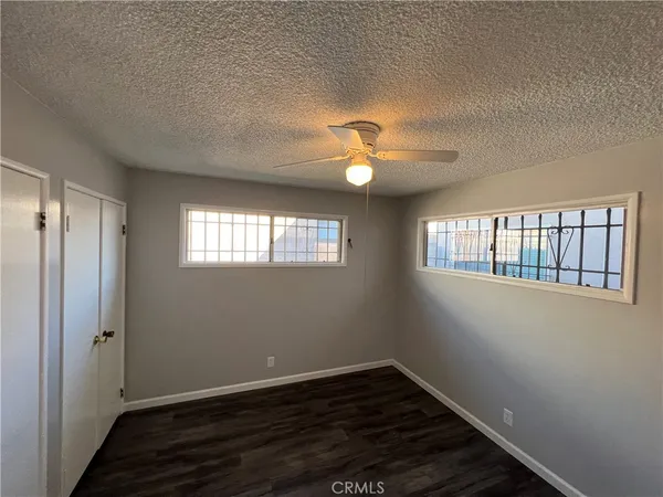 an empty room with wooden floor chandelier fan and windows