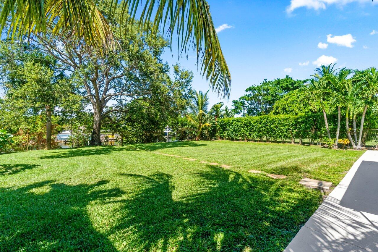 751 Hummingbird Way, Unit 7 North Palm Beach, FL 33408 - Photo 29 of 40 a view of a yard with a small plants and palm trees