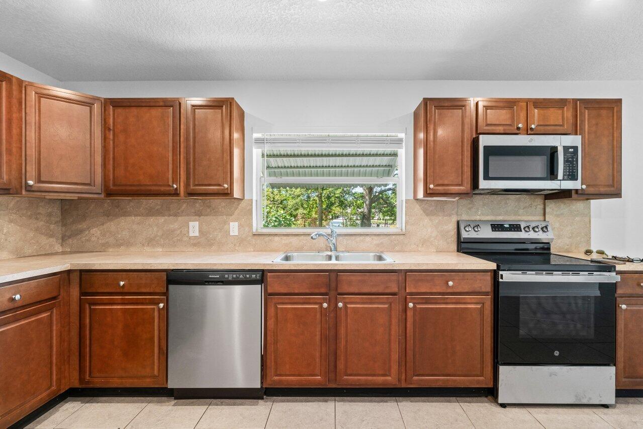 751 Hummingbird Way, Unit 7 North Palm Beach, FL 33408 - Photo 7 of 40 a kitchen with stainless steel appliances granite countertop a stove a sink and a microwave