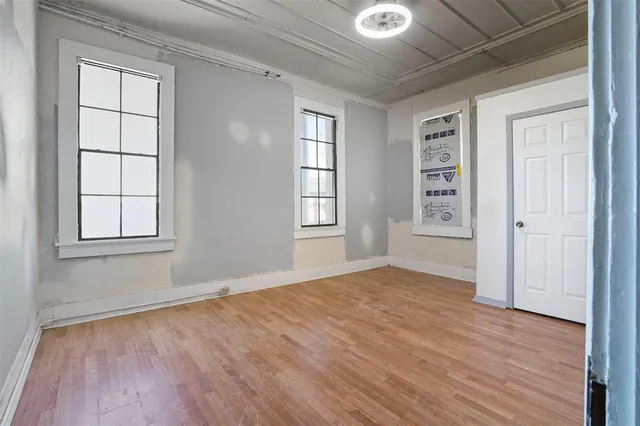 an empty room with wooden floor and windows