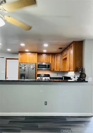 a view of a kitchen with stainless steel appliances granite countertop a sink a stove and a microwave oven