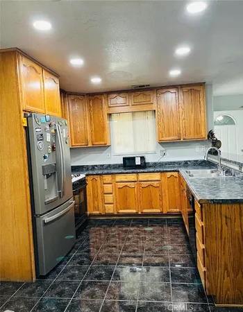 a large kitchen with granite countertop a sink and a refrigerator
