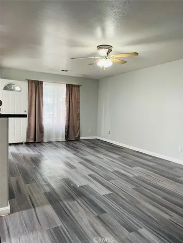 an empty room with wooden floor chandelier fan and windows