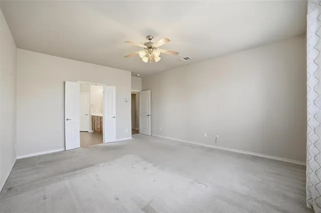 an empty room with a ceiling fan and a window