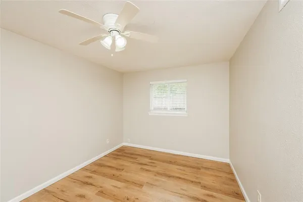 an empty room with a window and a fan