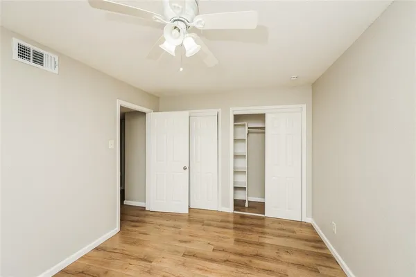 an empty room with closet and a ceiling fan