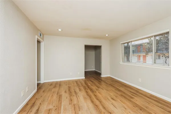 a view of an empty room with wooden floor and a window