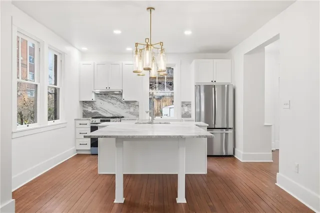 a kitchen with kitchen island stainless steel appliances a dining table chairs and wooden floor
