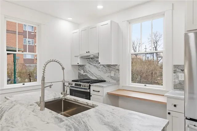 a kitchen with stainless steel appliances granite countertop a stove a sink and a refrigerator with wooden floor