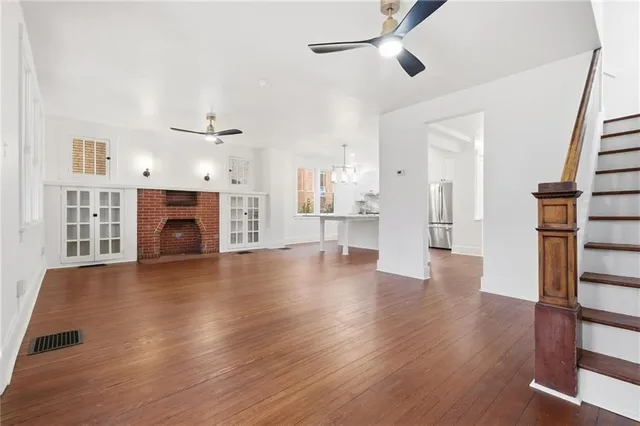an empty room with wooden floor a fireplace and windows