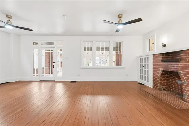 a view of an empty room with wooden floor and a fireplace