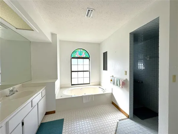 a spacious bathroom with a tub sink and mirror