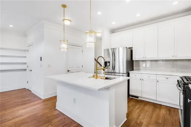 a kitchen with a sink a stove a refrigerator and white cabinets with wooden floor