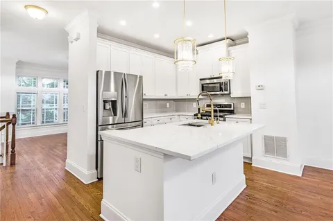 a kitchen with kitchen island white cabinets and stainless steel appliances