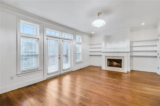 an empty room with wooden floor fireplace and windows