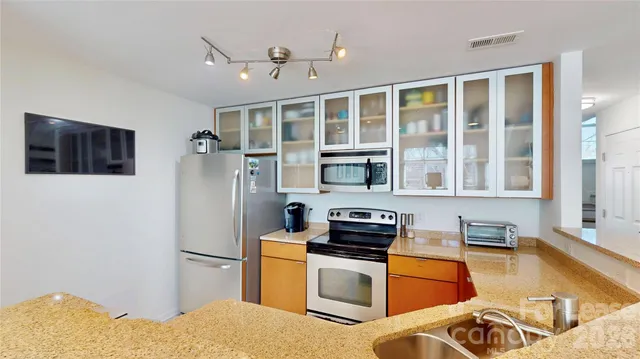 a kitchen with stainless steel appliances granite countertop a refrigerator a stove and a sink with granite countertops