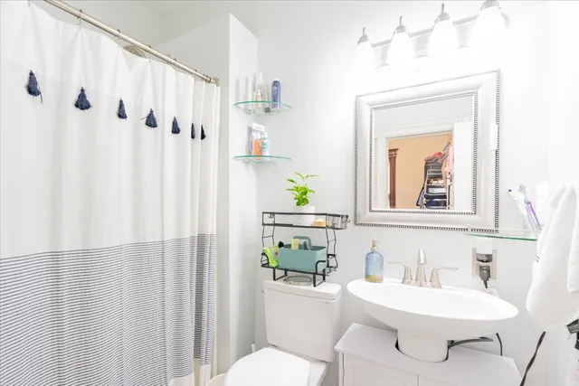a bathroom with a sink vanity mirror and toilet