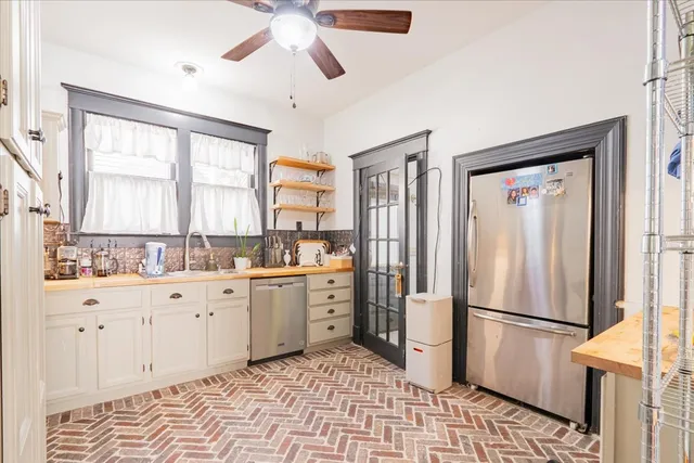 a kitchen with a refrigerator a sink dishwasher a stove and white cabinets with wooden floor