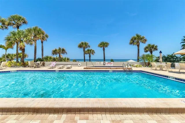 a view of a swimming pool with a bench and palm trees