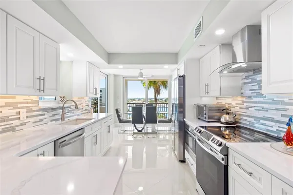 a view of a kitchen with kitchen island a sink stainless steel appliances cabinets and a counter top space