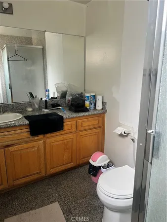 a bathroom with a granite countertop toilet sink and mirror