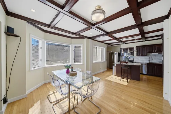 a kitchen with stainless steel appliances kitchen island granite countertop a table chairs in it and wooden floors
