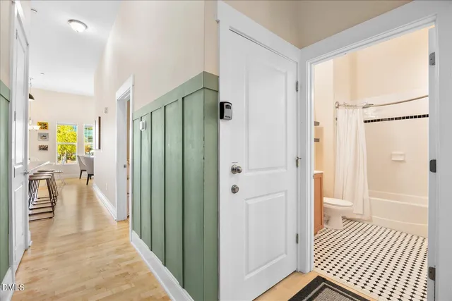 a view of a hallway with wooden floor and a bathroom