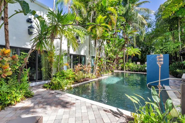 a view of swimming pool with lawn chairs and plants