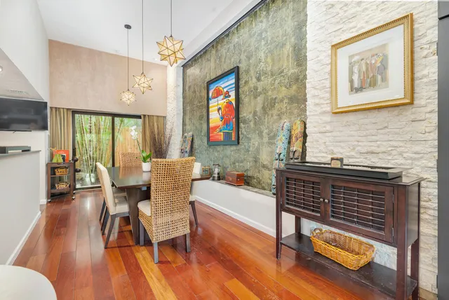 a dining room with wooden floor a chandelier a glass table and chairs