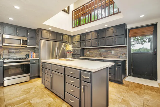 a kitchen with stainless steel appliances granite countertop a refrigerator and a stove top oven