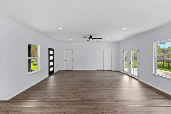 a view of an empty room with window and wooden floor